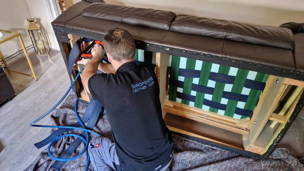 Installing new webbing straps under a sofa to restore seat support